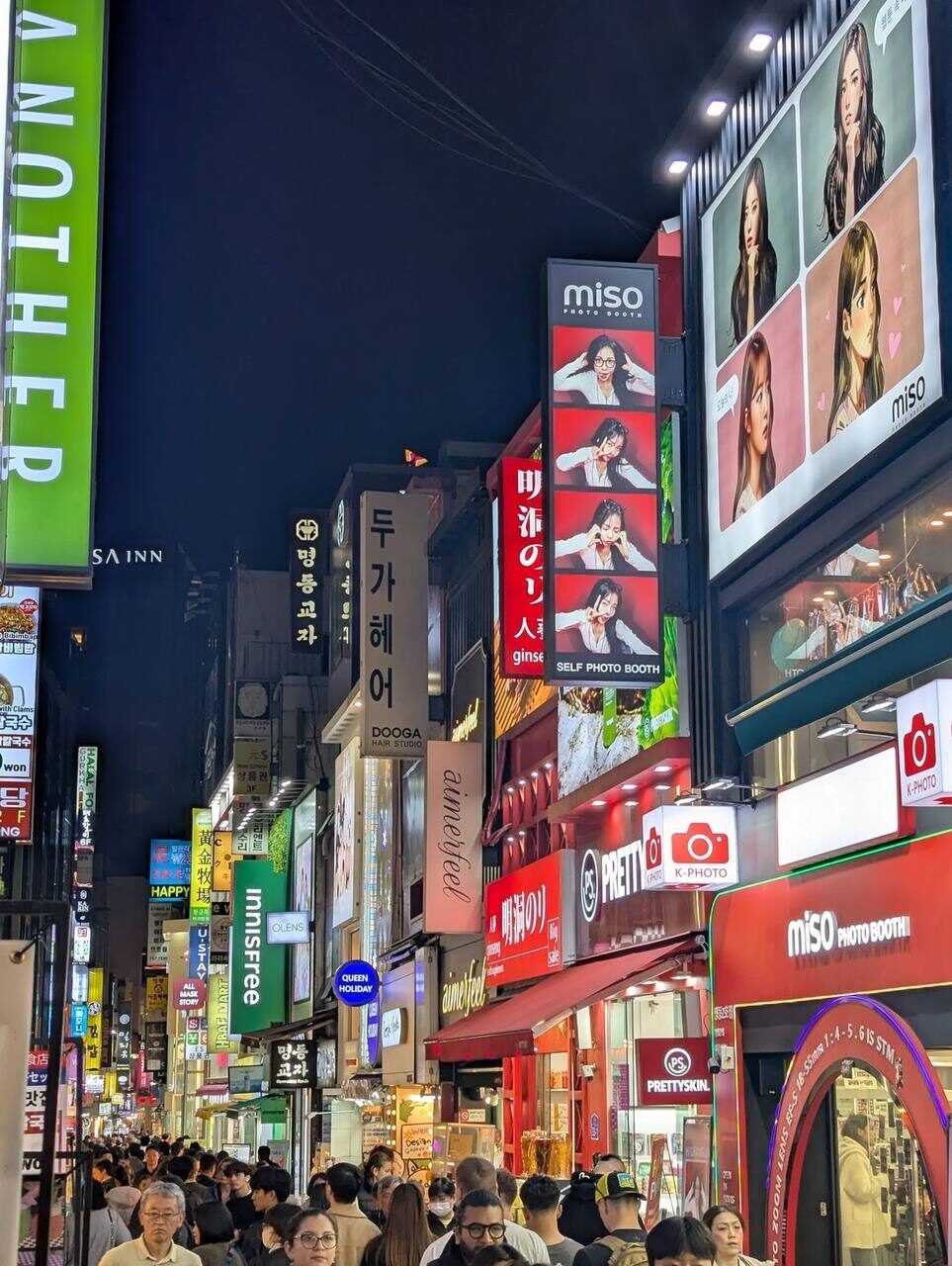 Calle comercial de Myeongdong de noche con letreros de neón y tiendas, Seúl