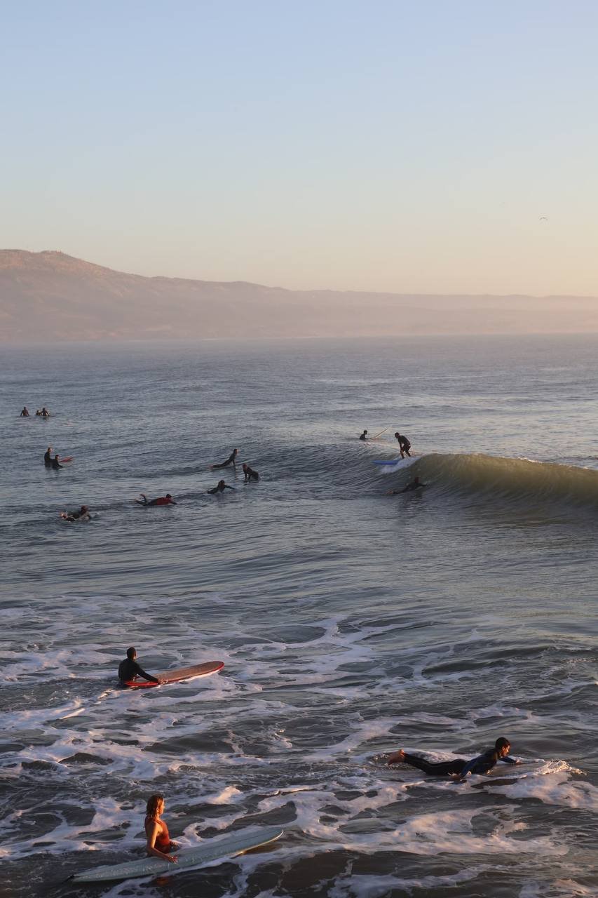 Grupo de surfistas en el agua al atardecer en Taghazout, Marruecos